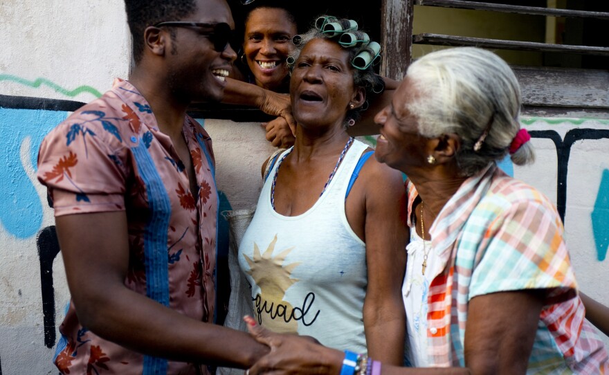 Cuban singer Erik Iglesias Rodriguez (left), who performs as Cimafunk, talks with women on the street in Havana.