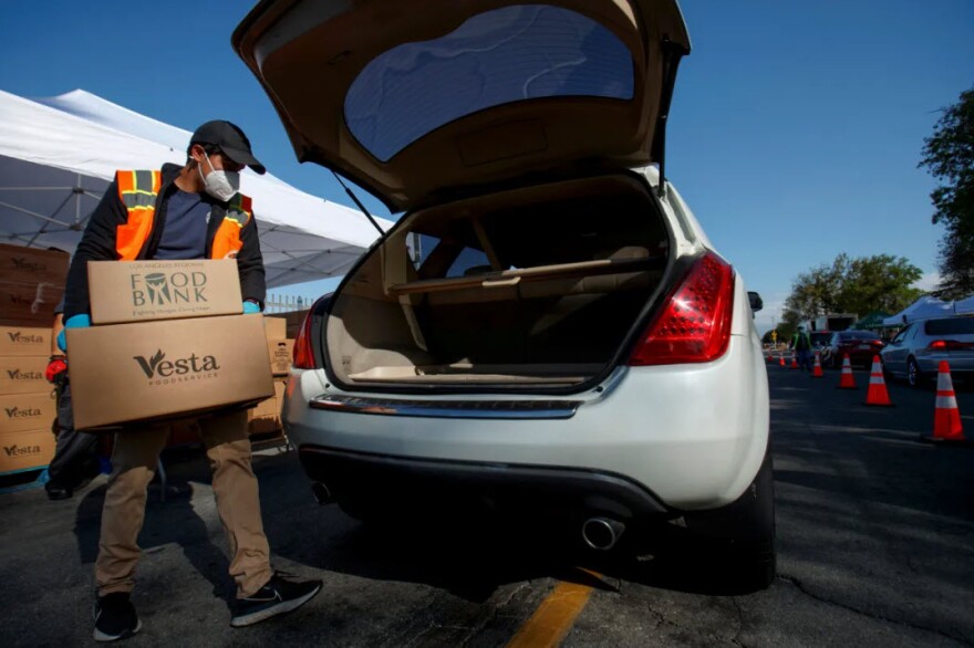 Anthony Torres loads a vehicle with food at the Los Angeles Regional Food Bank at Franklin D. Roosevelt Park in Los Angeles on March 23, 2021.