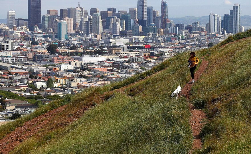 A dog walker on a dried section of Bernal Heights Park in 2014 in San Francisco (left). When Sullivan returned to the hillside this year, he was able to snap a photo of a woman walking her dog in almost the exact same spot.