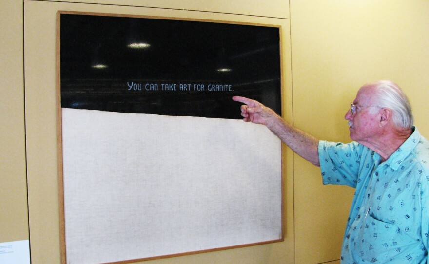 Artist Richard Allen Morris directs his attention to Russell Baldwin's "You Can Take Art For Granite," 1973, carved gabbro and canvas, 39.5" x 39.5" (second floor). Gift of Dr. Robert and Fran Preisman. San Diego Public Library Visual Arts Program Acquisition, City of San Diego Civic Art Collection 2013.133.