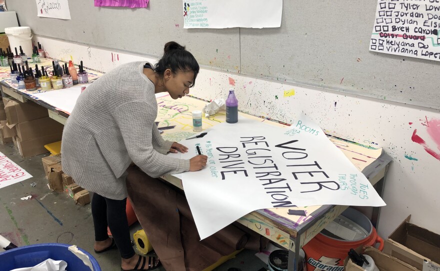Patrick Henry High School senior Ashlee Watson, 17, makes a sign to advertise a voter registration drive at her school, March 12, 2018.