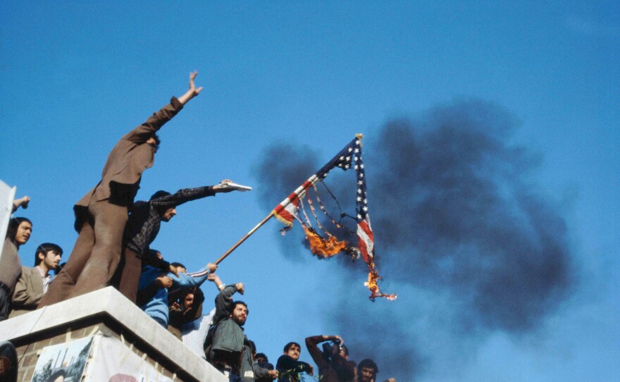 Iranians burn the American flag on the roof of the occupied U.S. embassy. June 1980.