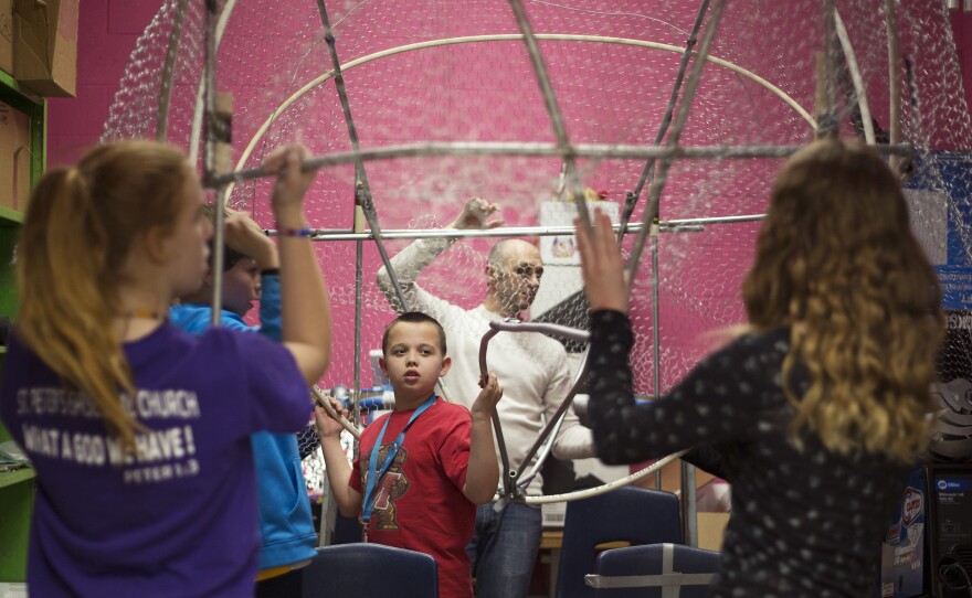Teacher Michael Guarraia helps members of the Arbutus Middle School Kinetic Club place the frame of their brain sculpture in the classroom closet.