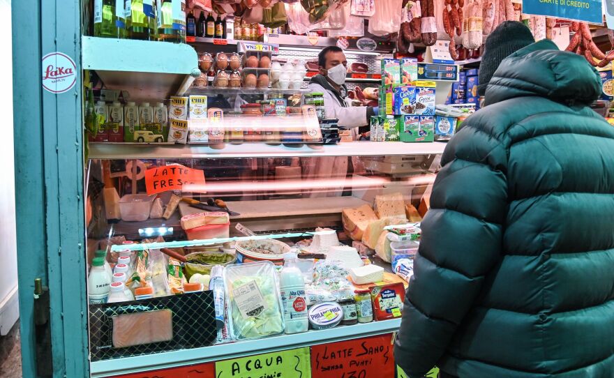 A vendor wearing protective masks and gloves serves a customer at a market in Rome on April 16.