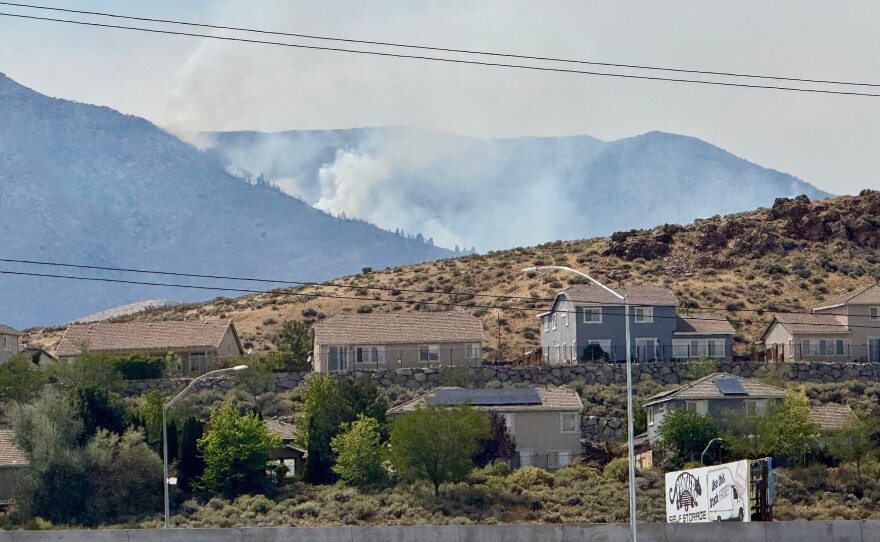 Smoke billows in the distance as a wildfire burns in Reno, Nev., Sunday, August 23, 2026. (AP Photo/Haven Daley)