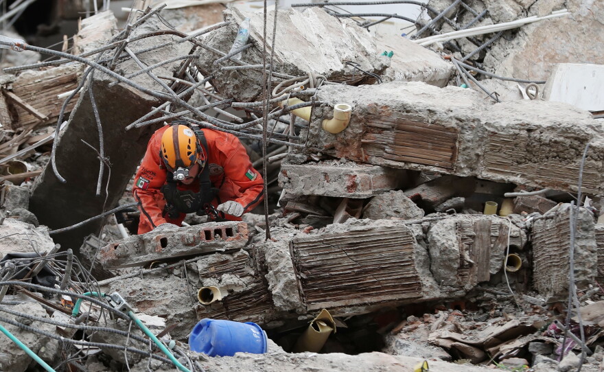 A Mexican rescue worker searches through the rubble two days after an earthquake struck Cali, Colombia, Wednesday, Aug. 12, 2026.