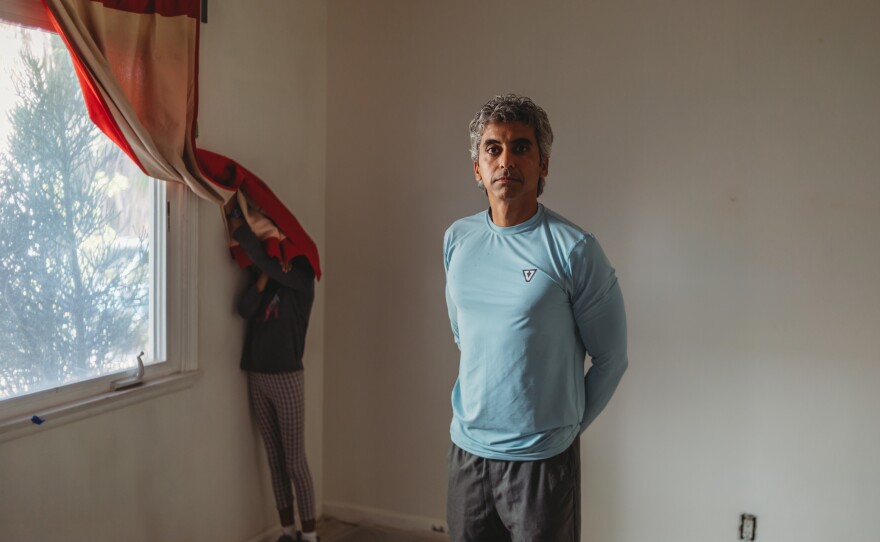 Nitin Bajaj poses inside one of the empty rooms inside the damaged apartment unit in Los Angeles, Calif., on October 2, 2021, with his youngest daughter Reva Bajaj, 9, in the background.