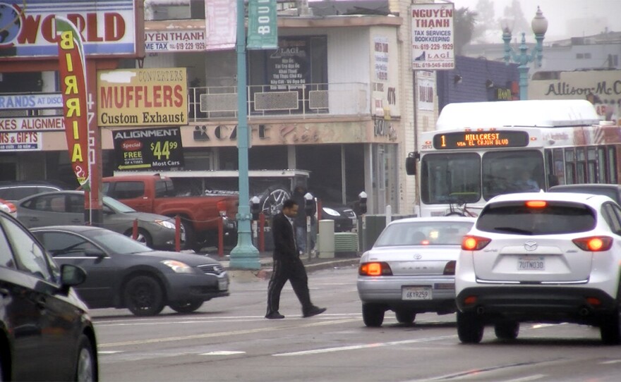 A pedestrian surrounded by cars crosses El Cajon Boulevard in City Heights, Jan. 11, 2017.