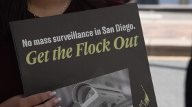 A protester holds a sign at a press conference announcing a lawsuit over the city of San Diego's use of Automated License Plate Reader technology on Sept. 30, 2026.