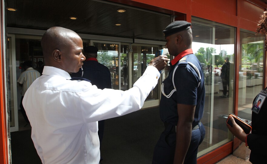 A security man takes visitors' temperatures Wednesday at the Transcorp Hilton hotel in Abuja, Nigeria, about 400 miles north of Port Harcourt.