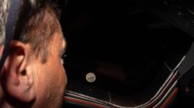Artemis II commander and NASA astronaut Reid Wiseman looks out one of the Orion spacecraft's main cabin windows at the moon ahead of the crew's lunar flyby. After successfully looping around the moon, the space capsule is now headed back toward Earth.