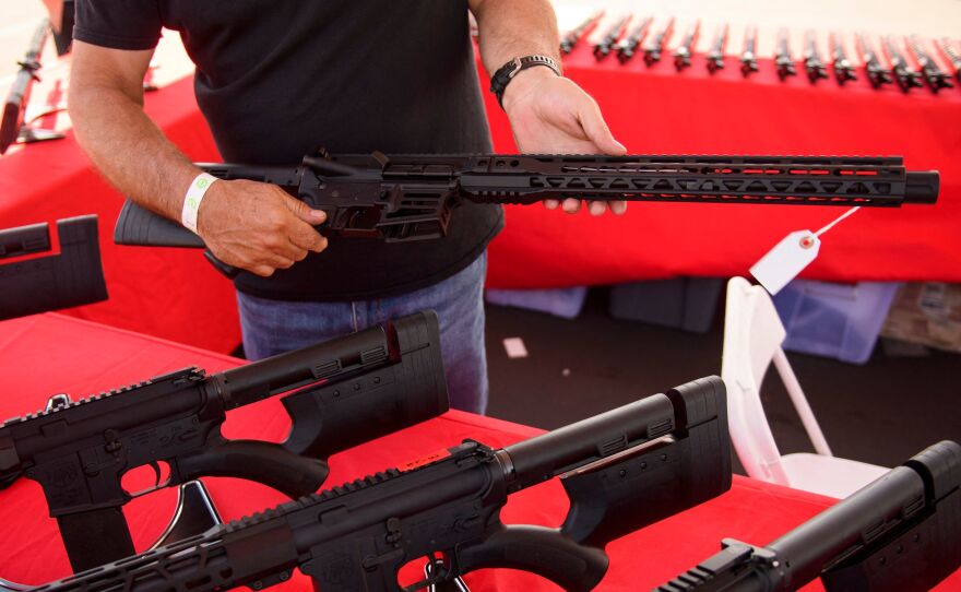 A clerk shows a customer an AR-15 style rifle at a gun show in Costa Mesa, Calif. in June 2021. Gun sales increased in the U.S, following COVID-19 pandemic lockdowns.