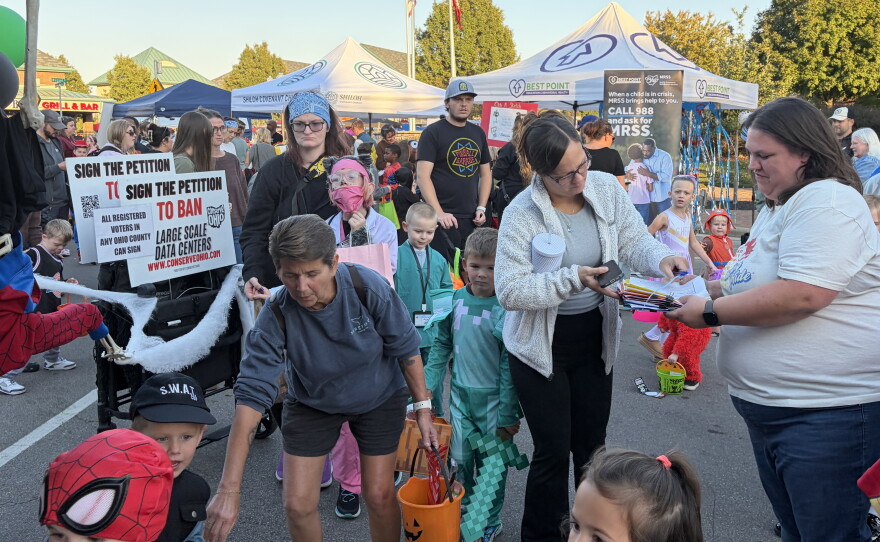 Linda Moodie (right), a volunteer with Conserve Ohio, collects signatures for a petition to ban large-scale data centers statewide at a Halloween event in Fairfield, Ohio, on Oct. 22, 2026.