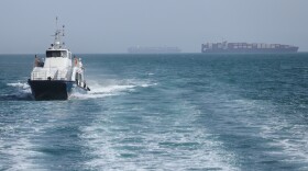 A patrol boat moves through the water as cargo ships sit at anchor in the Strait of Hormuz off Bandar Abbas, Iran, Saturday.