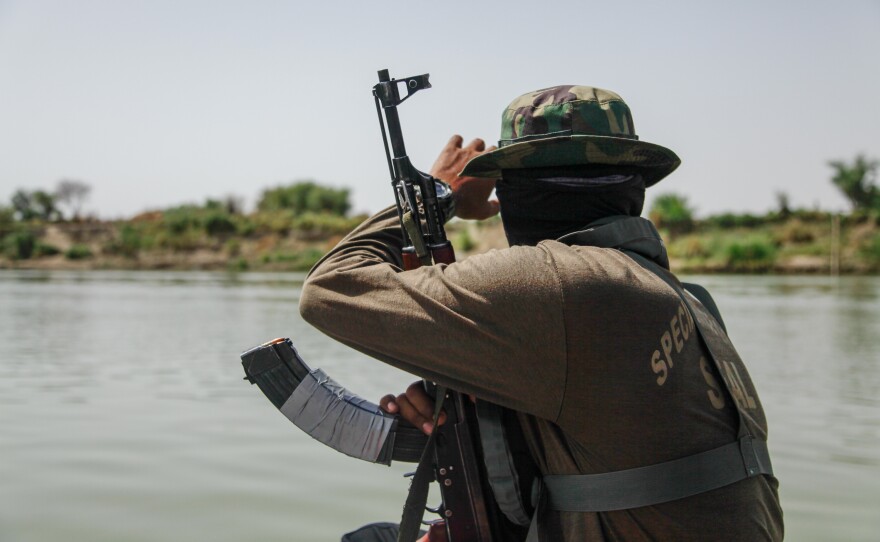 In this photograph taken in April 2022, a Pakistani naval officer guards a documentary team as they boat down a stretch of the Indus River near the southern Pakistani town of Sehwan. Researchers say one challenge they face in observing, or counting, the Indus River dolphin is the lack of security around the river. Outlaws live by the river banks and have attacked researchers in the past.
