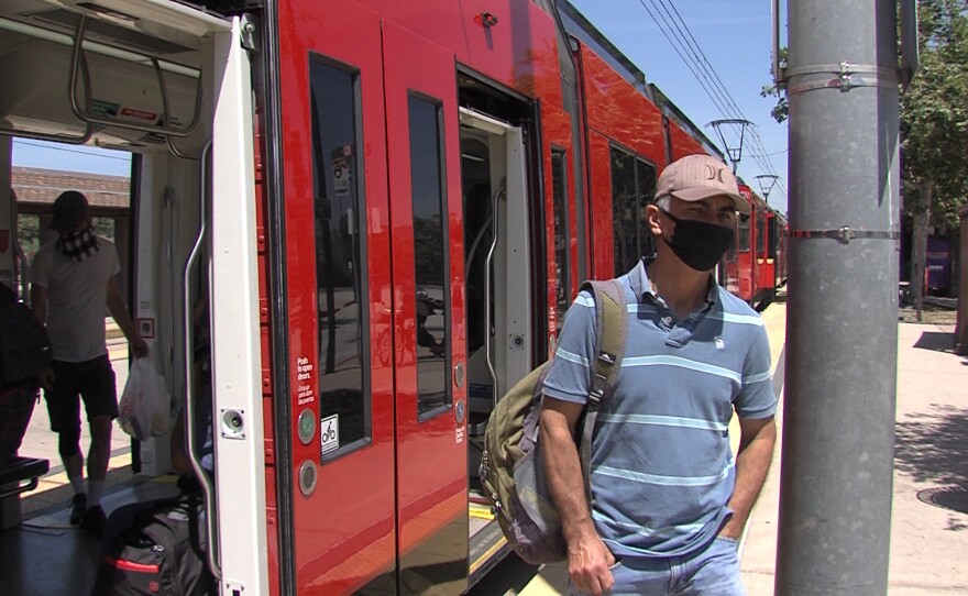 A man with a face covering exits an MTS trolley at the Old Town transit center, May 7, 2020.