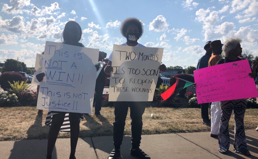 Sarah Jacobs and Anthony X hold signs in protest of the reopening of Tops supermarket after May's mass shooting there. They believe the site should have been turned into a memorial park and a new Tops built elsewhere in East Buffalo.