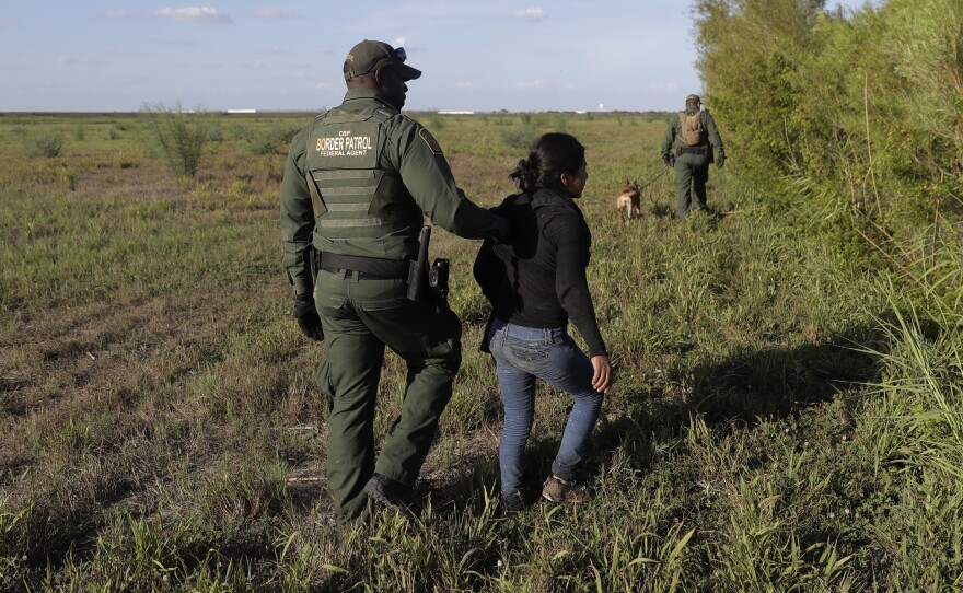A U.S. Customs and Border Patrol agent escorts an immigrant suspected of crossing into the United States illegally along the Rio Grande near Granjeno, Texas.
