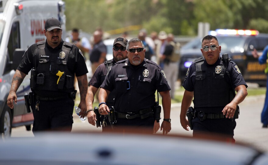 Police walk near Robb Elementary School following a shooting, Tuesday, May 24, 2022, in Uvalde, Texas. A gunman killed 14 children and a teacher, the governor said.