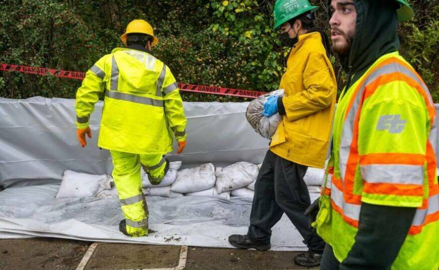 Members of the San José Conservation Corps pile sandbags along the San Francisquito Creek in East Palo Alto on Jan. 4, 2023. The creek spilled over its bank and into a nearby community during the storm on New Years Eve.