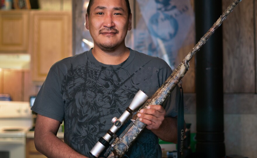 Noah Lincoln holds a gun his family uses for hunting. People in Toksook Bay rely on hunting and other subsistence activities.