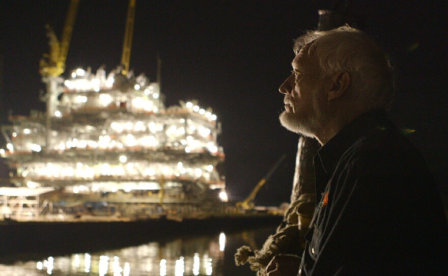 Tugboat captain Latham Smith in front of offshore oil rig construction.