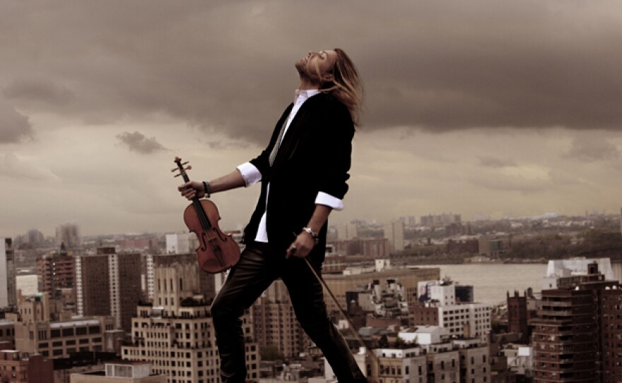 Promotional photo of musician David Garrett on a roof top with his violin.