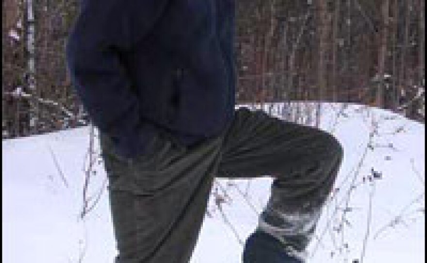 Roy Davis stands near a marker near his house that indicates where the U.S. ends and Canada begins. The woods are in Canada.