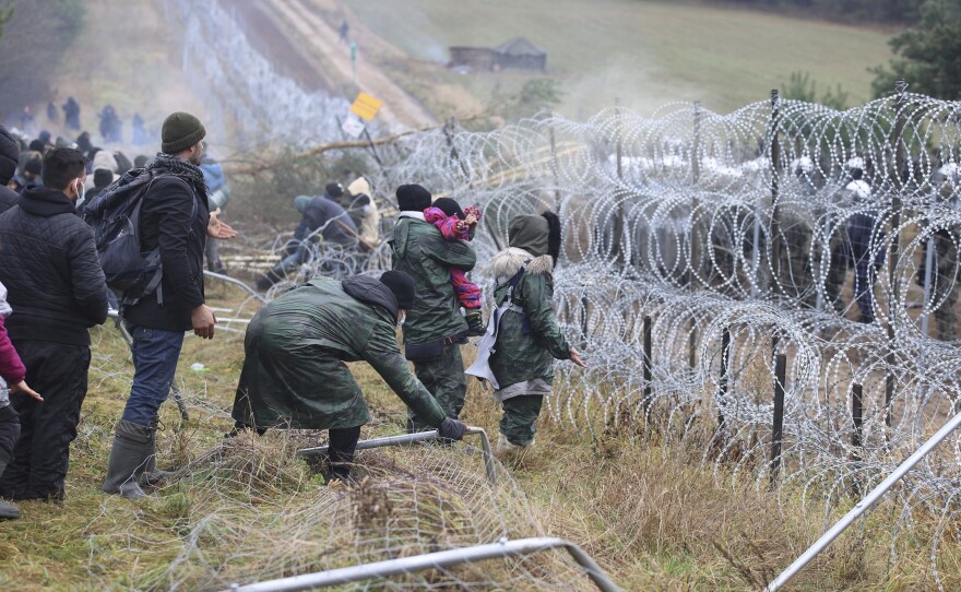 Migrants from the Middle East and elsewhere break down the fence as they gather at the Belarus-Poland border near Grodno, Belarus on Monday.
