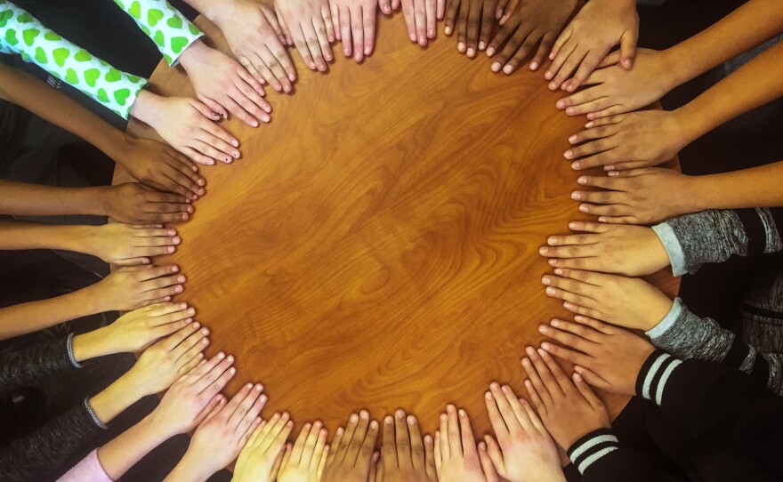 Students' hands gather in a circle in Tanya Streicher's class at Gilpin Montessori School in Denver.