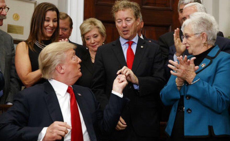 President Trump hands a pen that he used to sign an executive order on health care to Sen. Rand Paul, R-Ky., in the Roosevelt Room of the White House on Thursday.