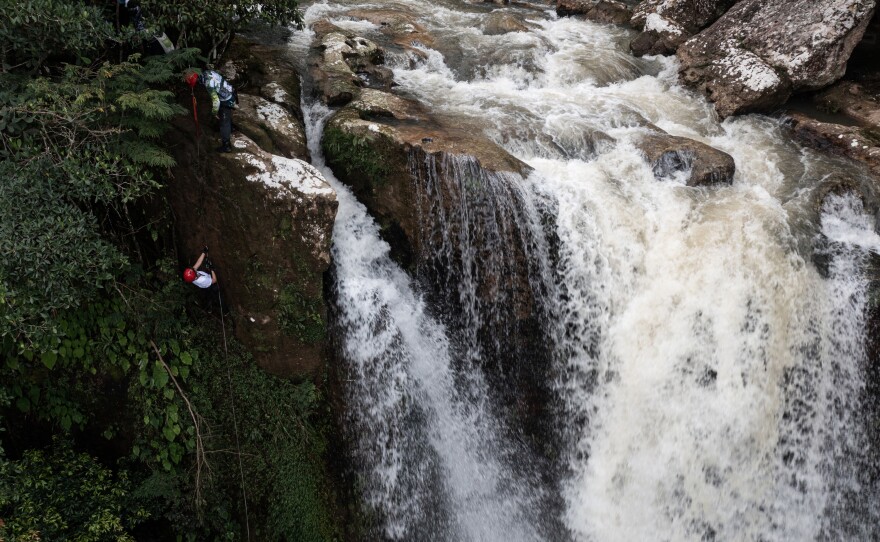 A tourist rappels next to a waterfall.