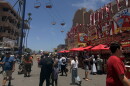 Visitors walk down a food-vendor lined walkway as the gondola ride passes overhead at the San Diego County Fair on June 10, 2026.