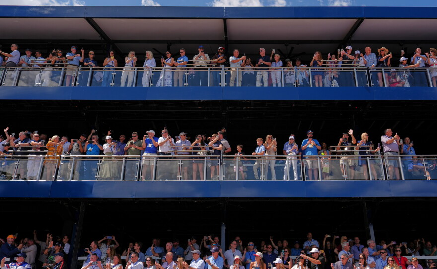 Spectators watch as President  Trump, in the presidential limousine known as "The Beast," does a lap around the track before the IndyCar Freedom 250 Grand Prix auto race.