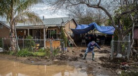 A resident shovels mud deposited by flooding from his driveway in Cutler on March 12, 2023.