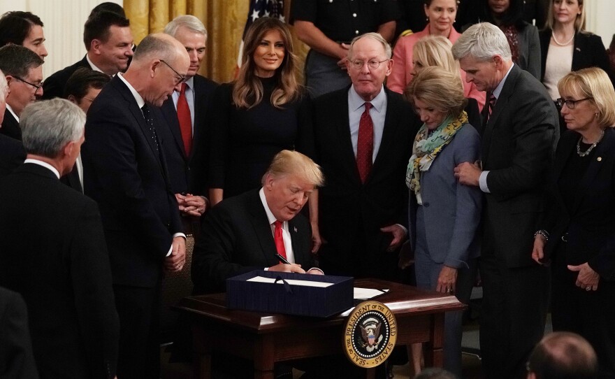 Flanked by lawmakers and first lady Melania Trump, President Trump participates in a bill signing to dedicate more resources to fight the opioid crisis during an East Room event at the White House Wednesday.