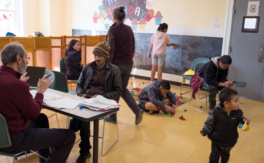 Russ Altone (left), co-organizer of Refugee Community Health Partnership at the Trinity Alliance, helps resettled refugees at the weekly walk-in session. Trinity Alliance provides food, medical assistance and other services.