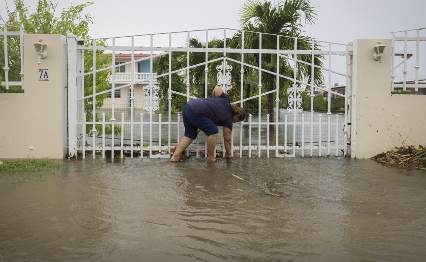 A woman clears debris on her property flooded by Hurricane Fiona in Salinas, Puerto Rico, Monday, Sept. 19, 2022.