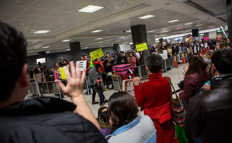 Demonstrators cheer passengers exiting international flights at Washington Dulles International Airport in D.C.