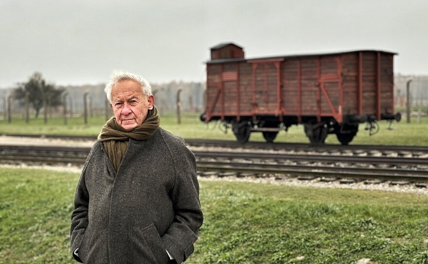 Simon Schama standing in front of a train carriage at Auschwitz-Birkenau. (undated photo)