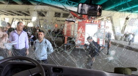 Syrians appear behind the damaged windshield of a minibus as they inspect the site of a blast in the central Midan district of Damascus last month. A new jihadist organization in Syria claimed responsibility for the attack.