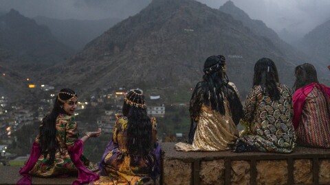 Girls sit on a wall to get a good vantage point of people walking up the mountains with flaming torches and fireworks for Nowruz in Akre, the Kurdish region of Iraq on Friday.