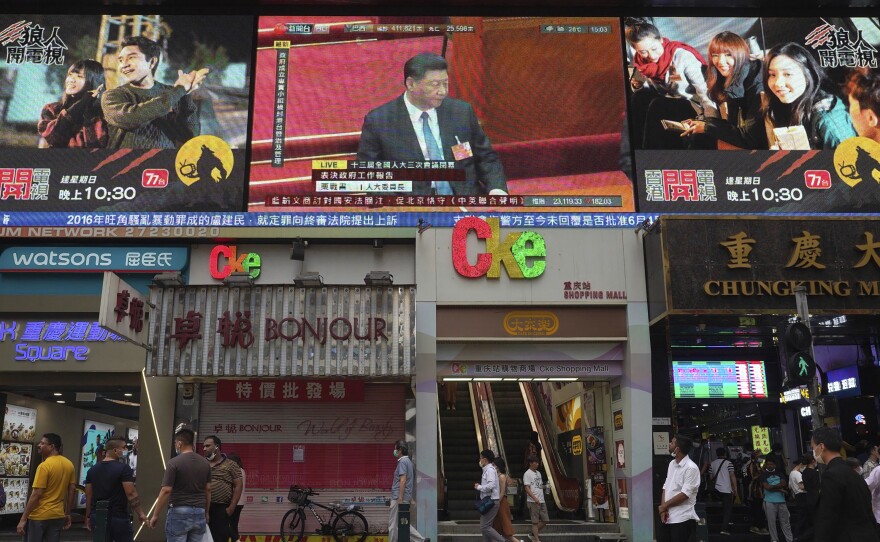Pedestrians in Hong Kong walk under a giant screen showing a live telecast of Chinese President Xi Jinping, at the closing session of the National People's Congress on Thursday.