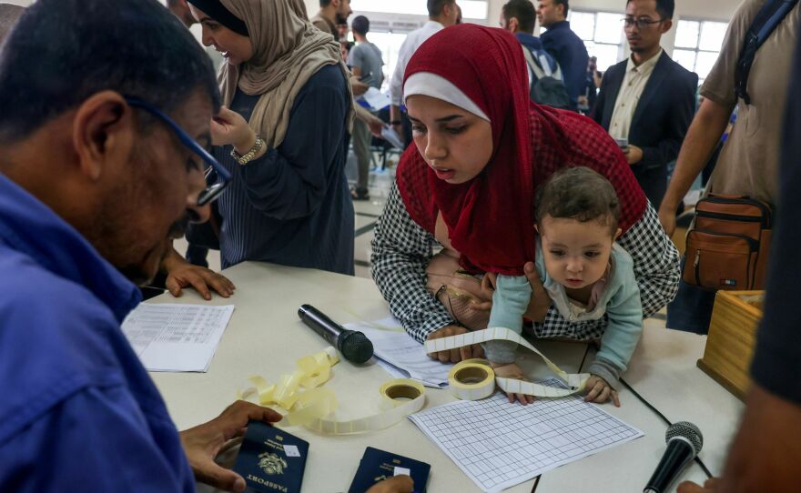 Civilians leaving Gaza display their documents as dual national Palestinians and foreigners prepare to cross the Rafah border point with Egypt, in the southern Gaza Strip, on  Thursday.