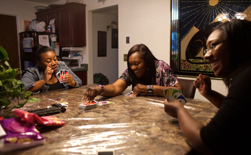 Loretta Jackson, center, plays a card game with her daughters Onasha Mitchell and Johkida Jackson on a Friday evening at home.
