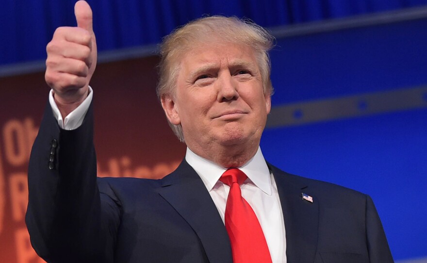 Donald Trump flashes the thumbs-up as he arrives on stage for the start of the prime time Republican presidential debate on August 6, 2015.