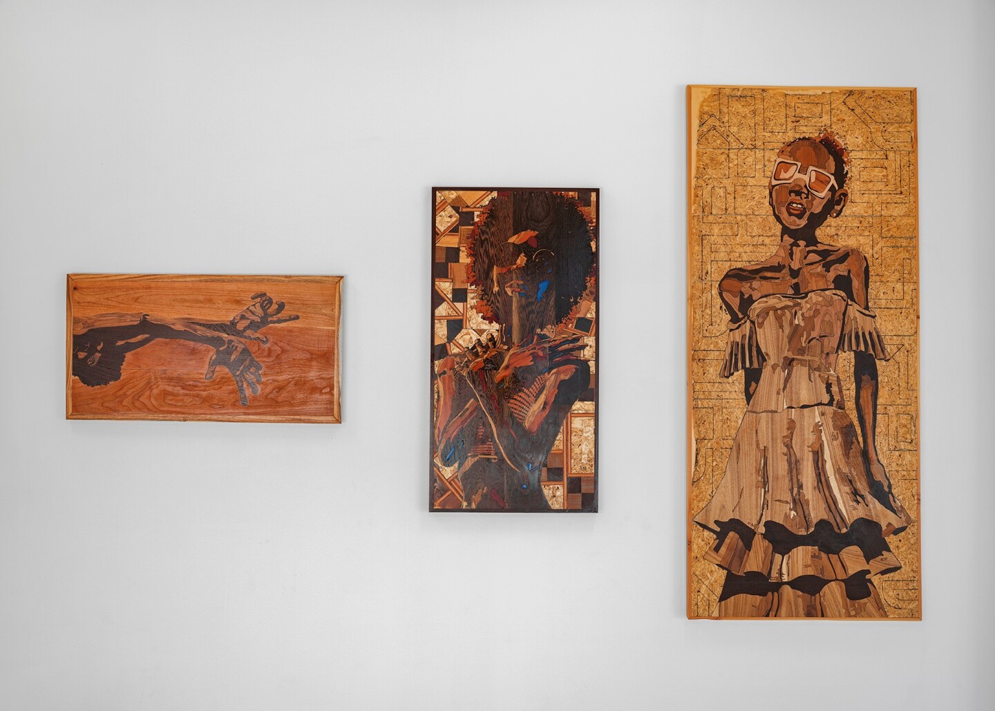 Flat, 2-dimensional wooden sculpture-paintings feature hands, and portraits.