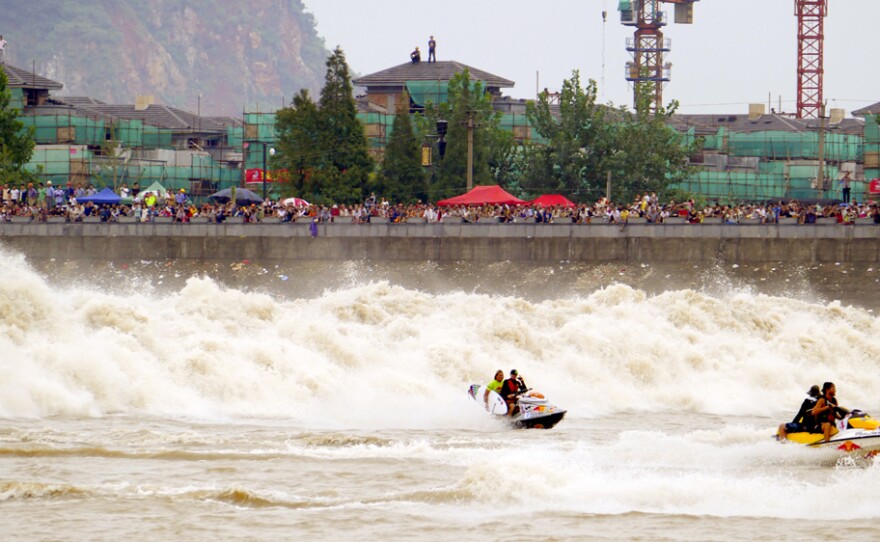 Surfers race in front of the Qiantang Tidal Bore. The wave, which travels upriver, forms during China's Mid-Autumn Festival, when the moon is full.