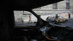 A woman walks past burned-out cars after a quiet night Monday under curfew, the first since weekend protests over the cost of living turned into rioting and looting across France, in Paris, Tuesday, Oct. 20, 2026.