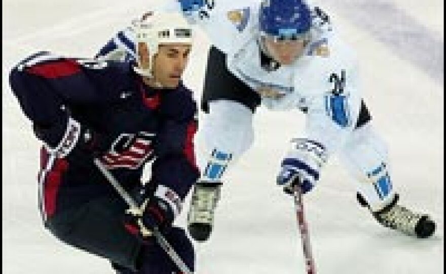 Jere Numminen of Finland, right, is defended by Mathieu Schneider of the United States during a quarter-final men's ice hockey match, Feb. 22, 2006.